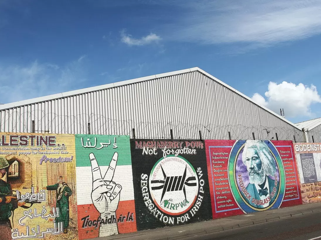 Falls Road Murals on the Falls Road. Belfast, Ireland. A row of political murals against the barbed-wire dividing wall. 