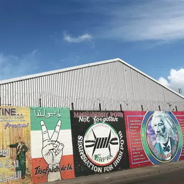 Falls Road Murals on the Falls Road. Belfast, Ireland. A row of political murals against the barbed-wire dividing wall. 