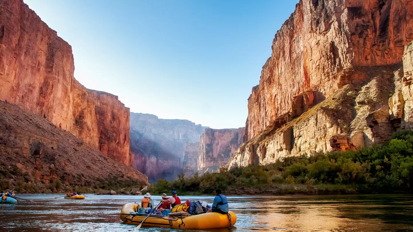Yellow raft on the Colorado River in the Grand Canyon, blue sky, canyon reflections