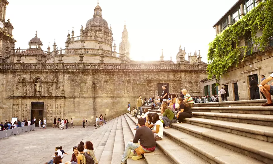 Visitors sitting on steps outside Santiago de Compostela Cathedral.