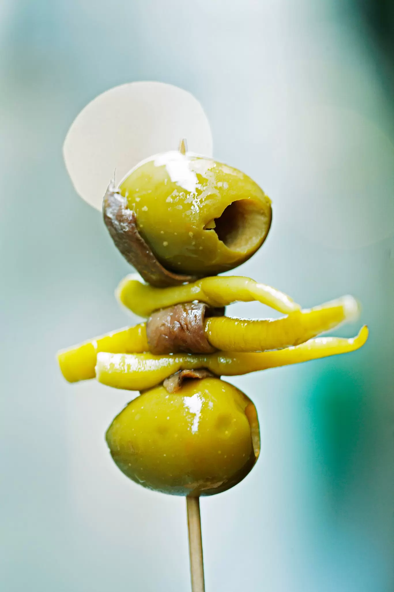 An olive, anchovy and pickle on a cocktail stick in Spain
