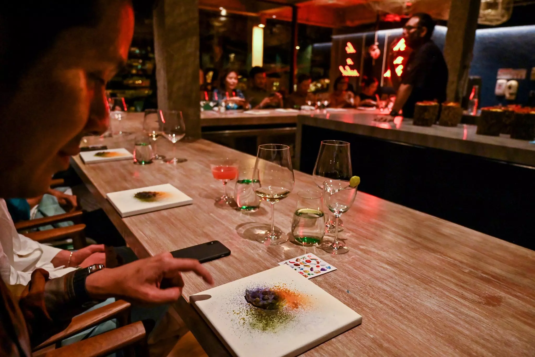 A diner looks at a dish at a haute cuisine restaurant with atmospheric lighting.