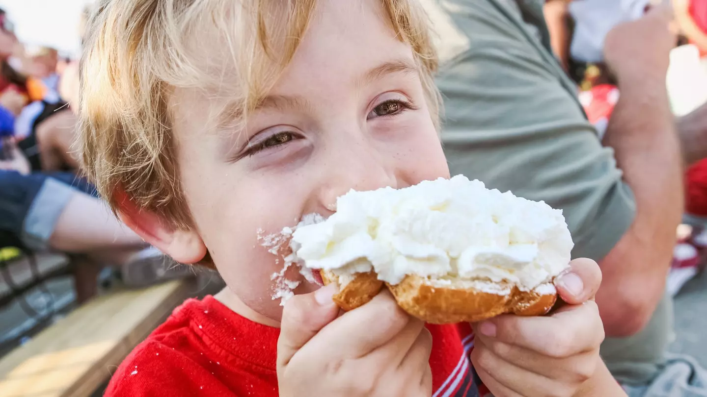 Young boy eating a whipped cream puff pastry at the Wisconsin State Fair, Milwaukee, Wisconsin, Great Lakes, USA
