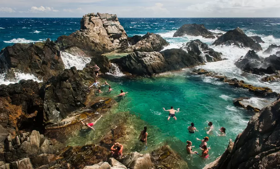 Visitors swimming in a protected rock pool on the north coast of Aruba.