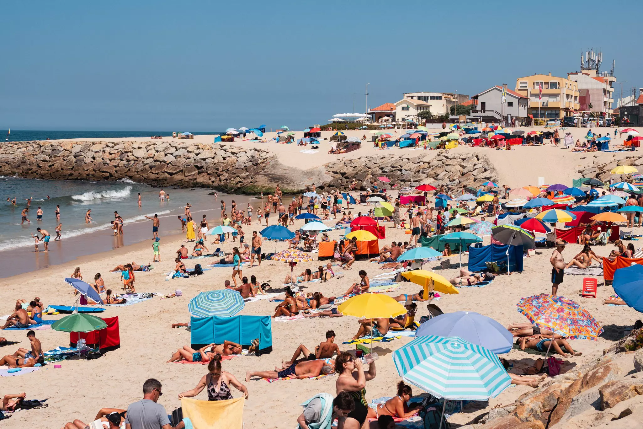 Clusters of people and colorful umbrellas on a beach