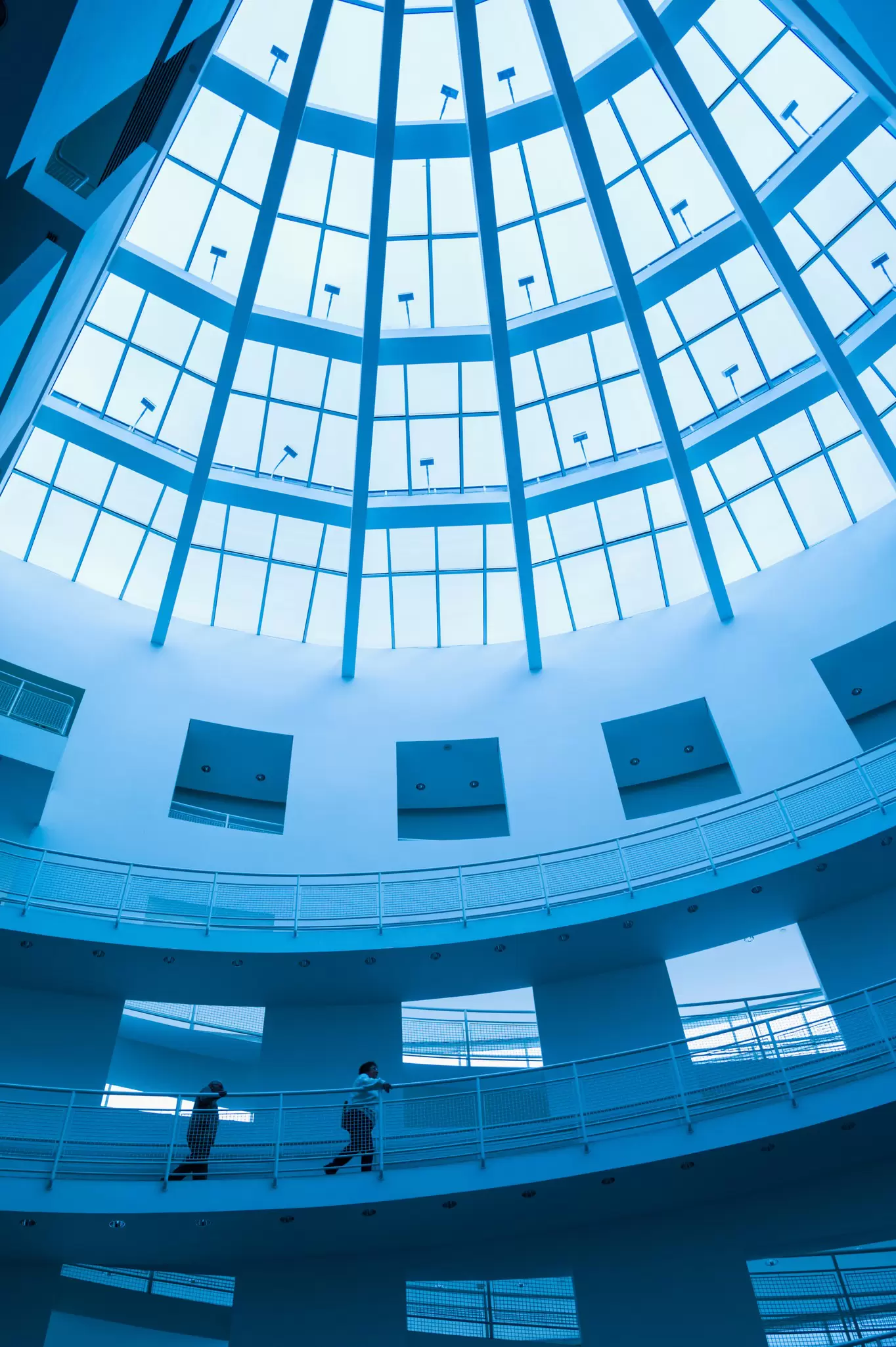 A light-filled atrium with white walls and ramps running up the side of it