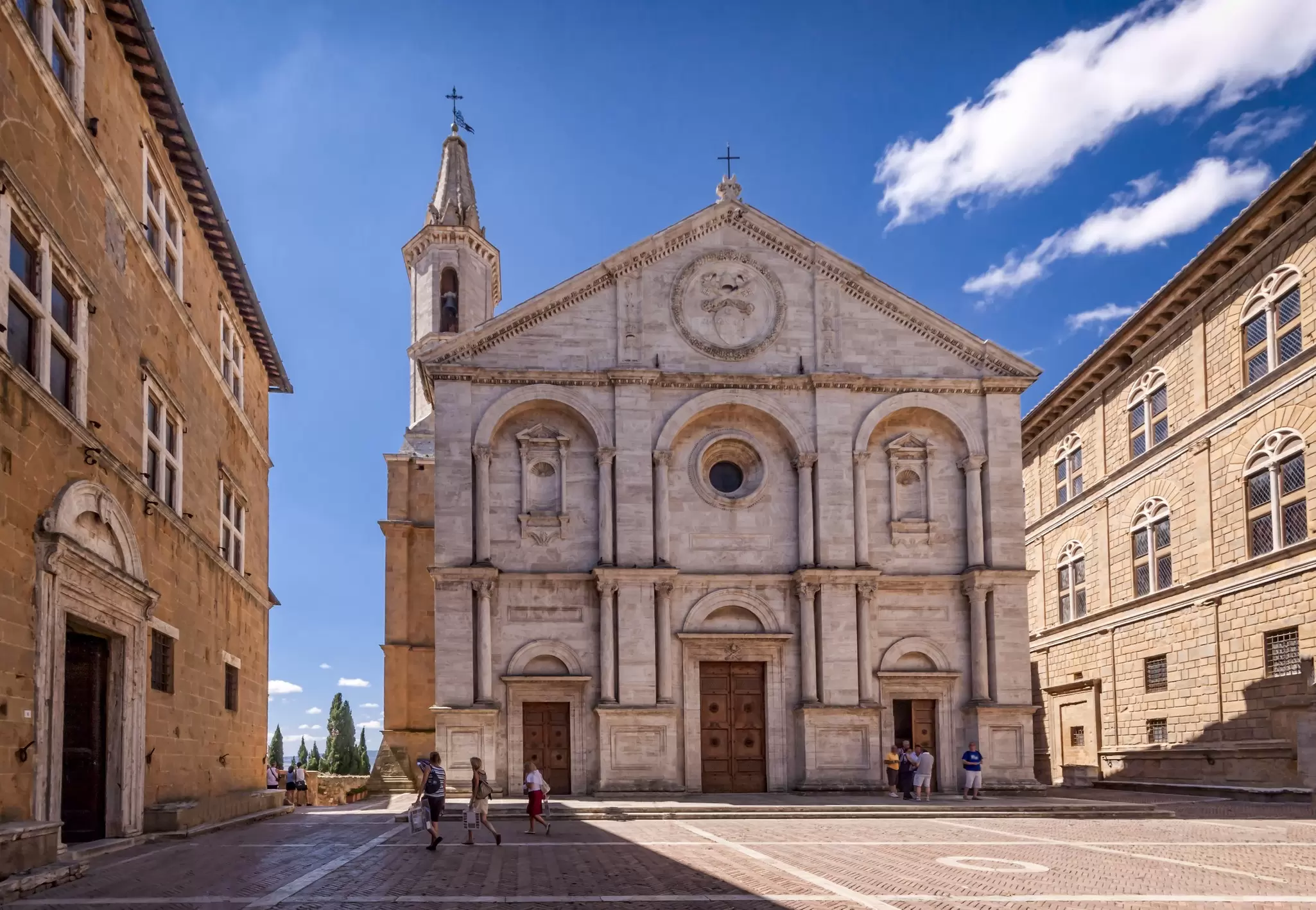 View from Pienza Square on a sunny day with the Piazza Pio II church towering in the background.