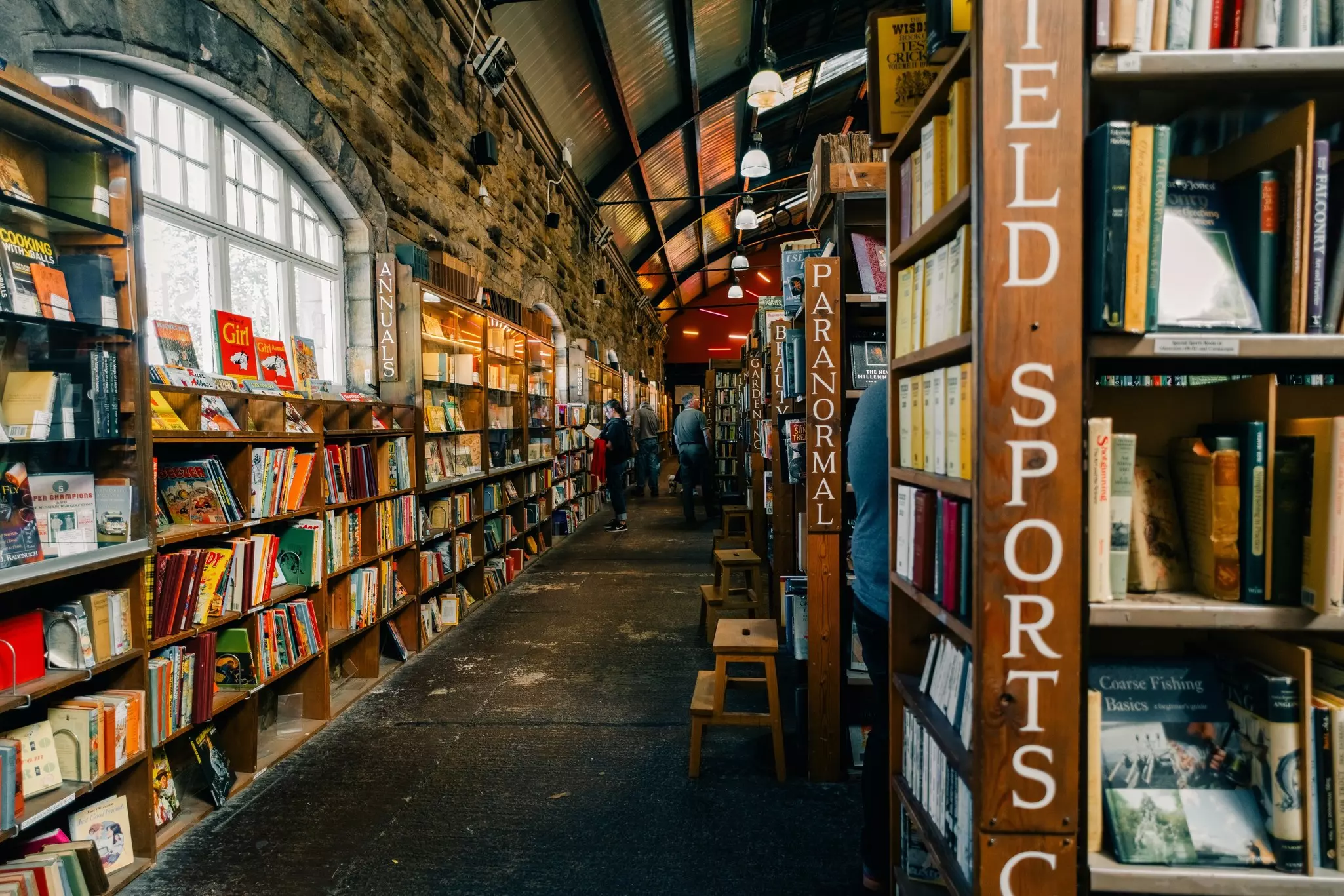 A large building resembling a train station lined in shelves that are stuffed with books.