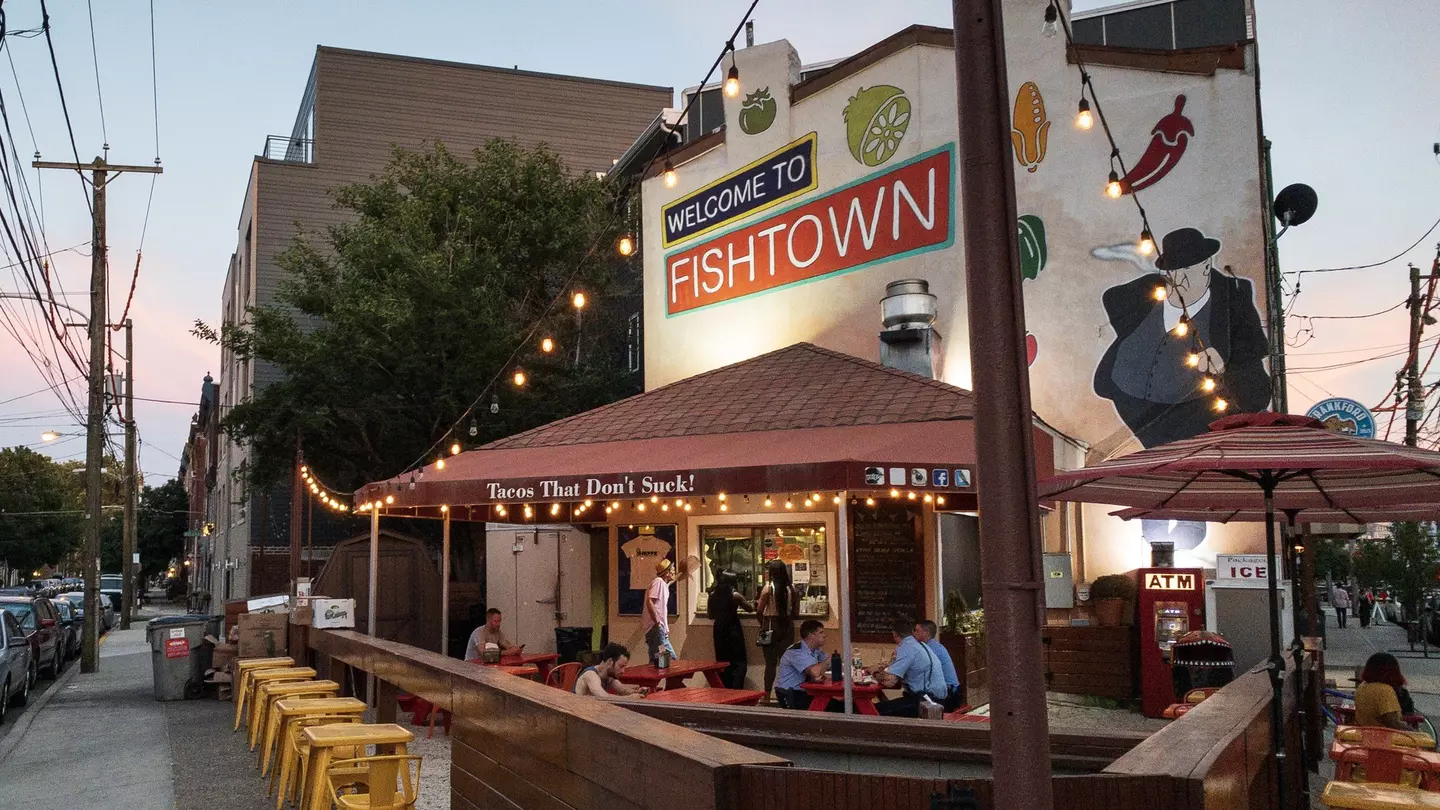 A few people sit at tables at a restaurant with outdoor dining in  the Fishtown area of North Philadelphia