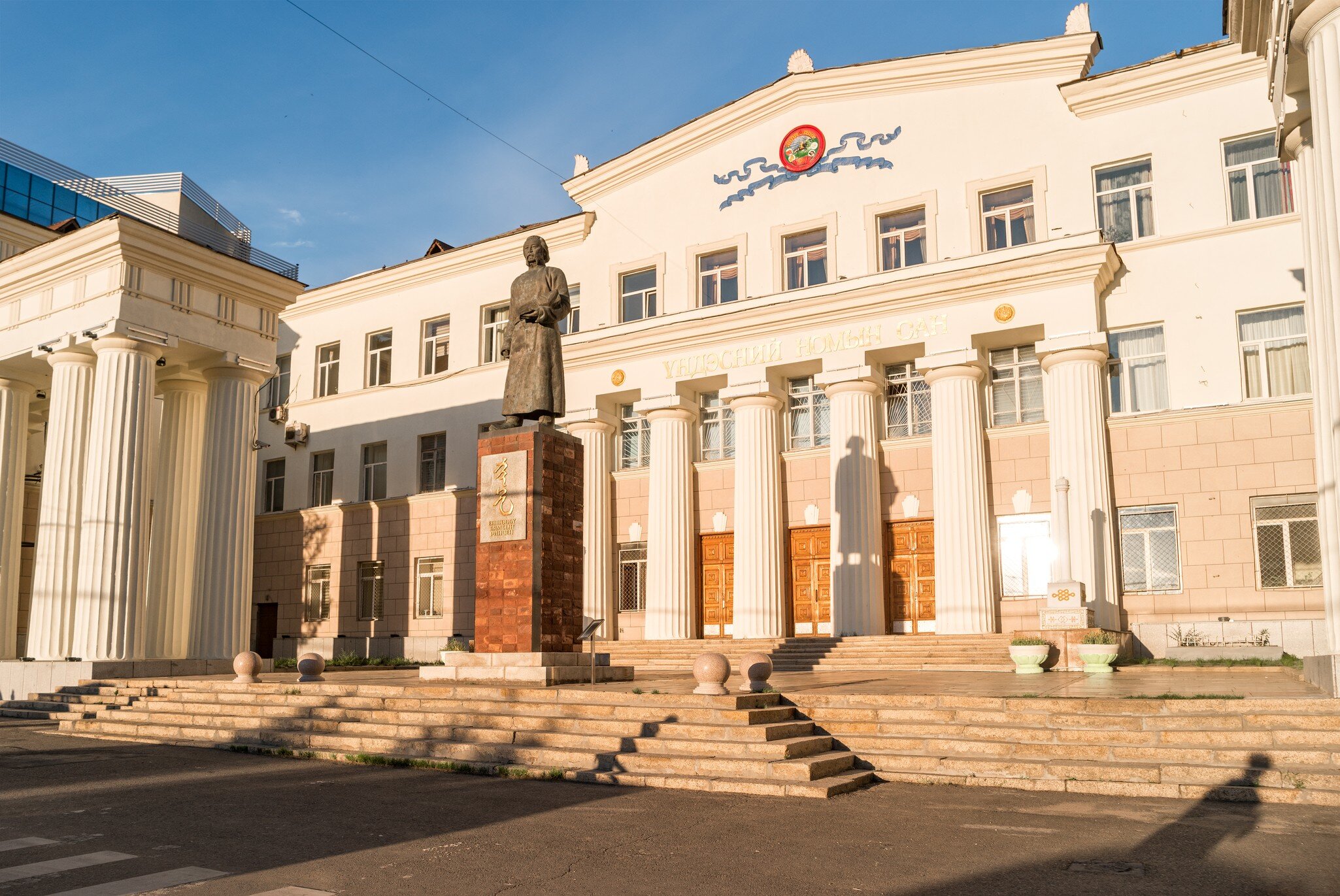 Statue of Byambyn Rinchen before the columned National Library of Mongolia, Ulaanbaatar; facade reads ҮНДЭСНИЙ НОМЫН САН