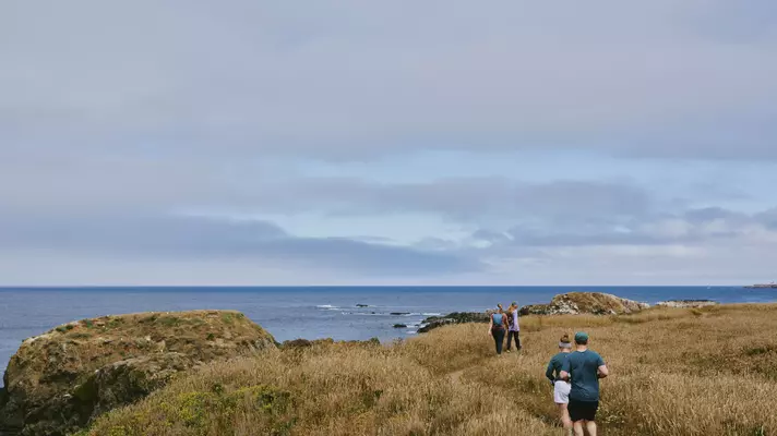 People hike a rugged cliff trail