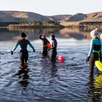 A group in wet suits ready to go to wild swimming in a freshwater reservoir in Scotland