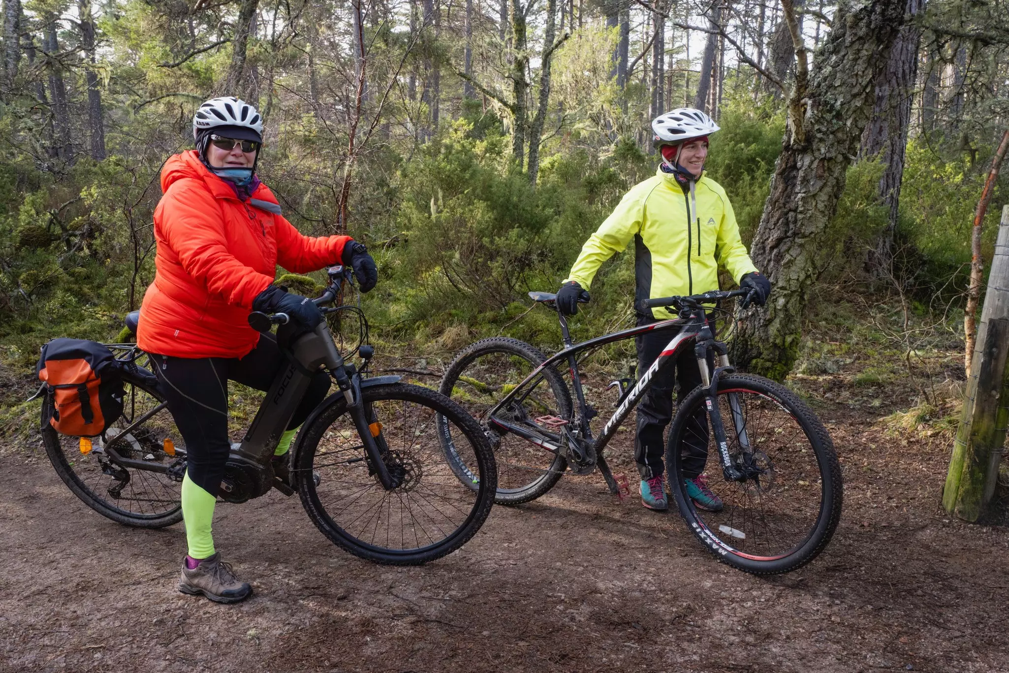 Two cyclists in the woods carry their bikes during a cyclocross race at Russian Jack Springs Park