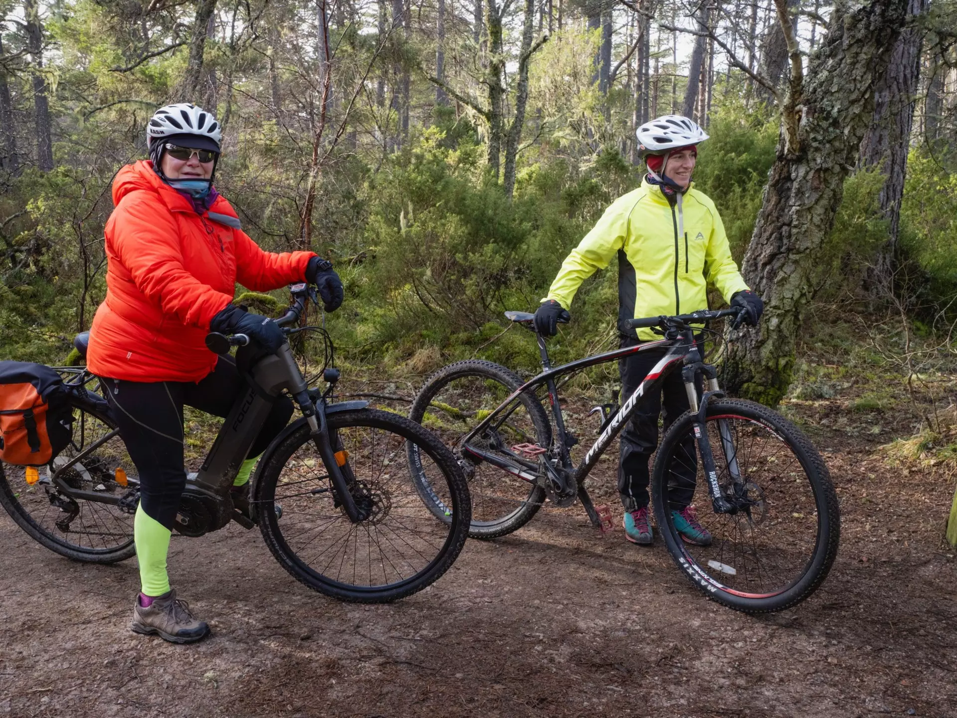 Two cyclists in the woods carry their bikes during a cyclocross race at Russian Jack Springs Park