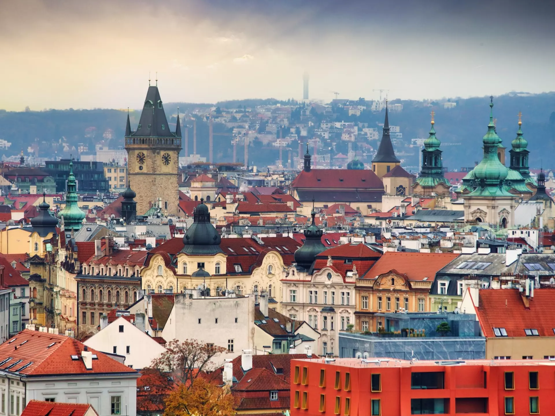 A panoramic view of the skyline of a city showing red-tiled roofs and church spires