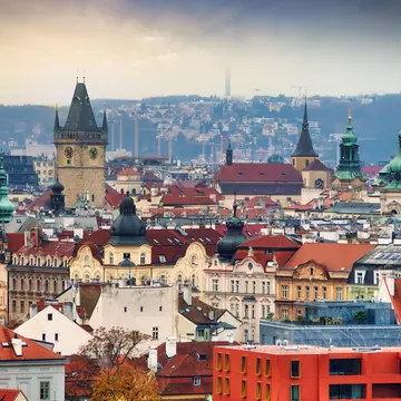 A panoramic view of the skyline of a city showing red-tiled roofs and church spires