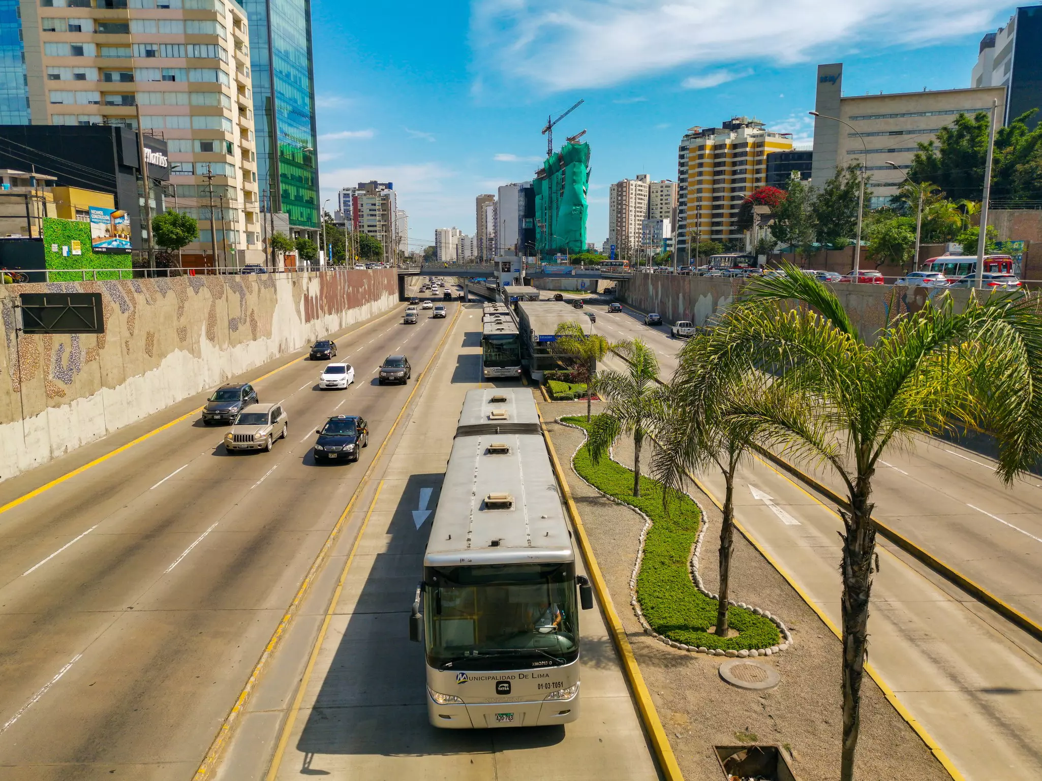 An overhead view of a bus traveling in a dedicated lane on a highway in a city.