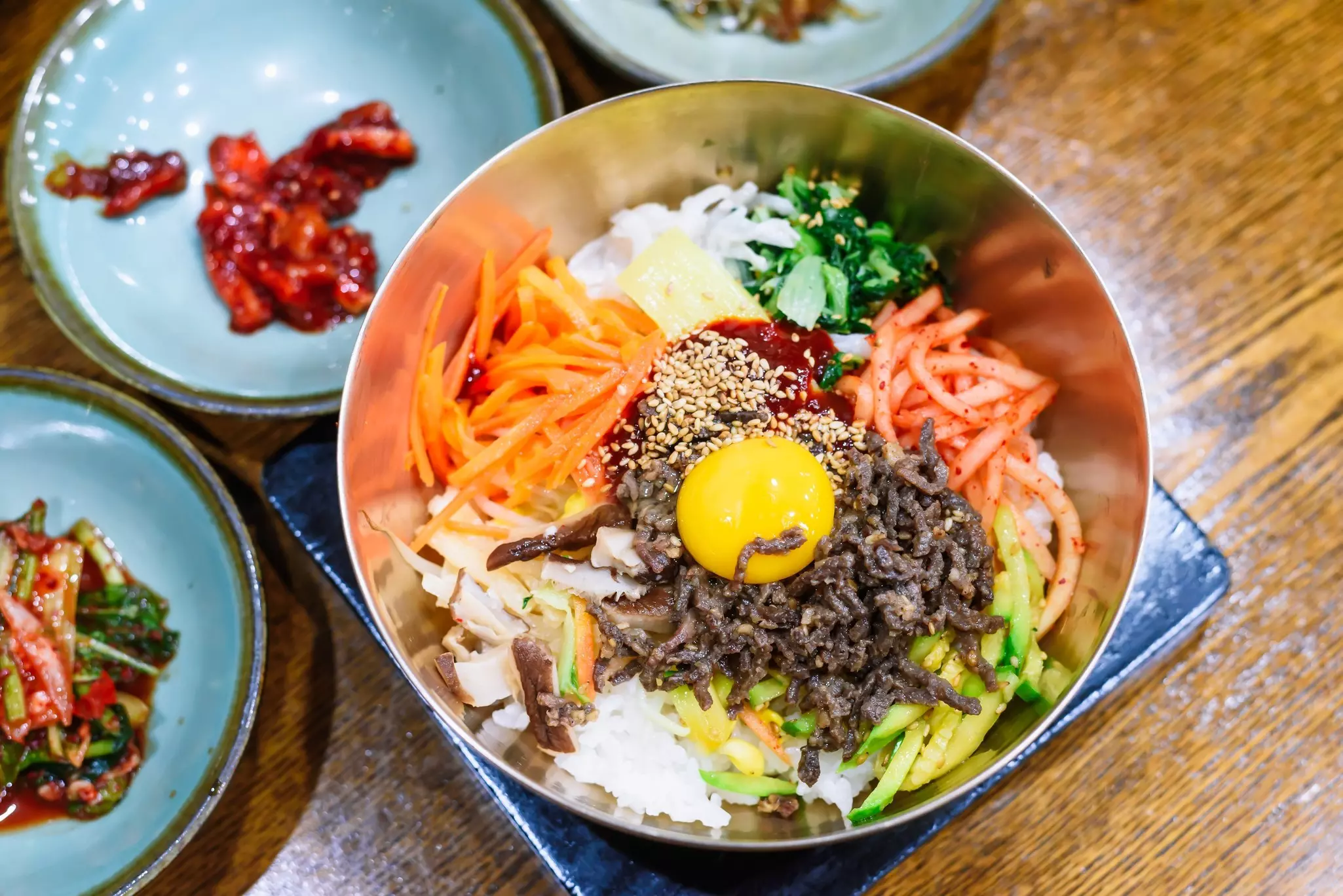 Traditional Korean bibimbap in a brass bowl with raw egg yolk and colorful vegetables