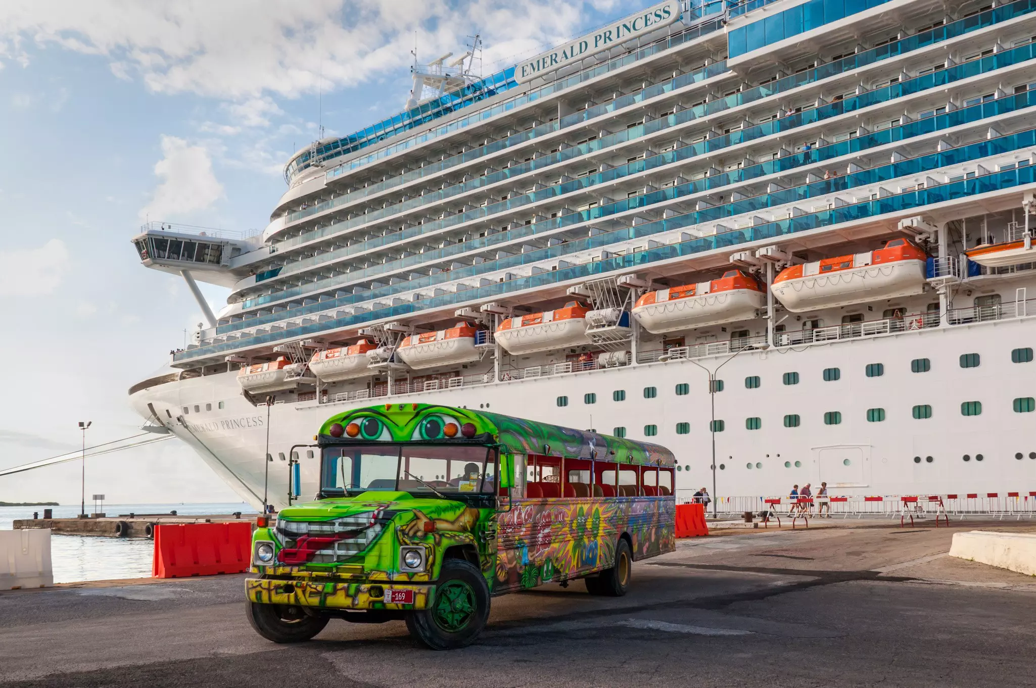 A Princess Cruise Line cruise ship docked in Oranjestad. A colorful tour bus waiting for the next group of tourists for a fun island tour.