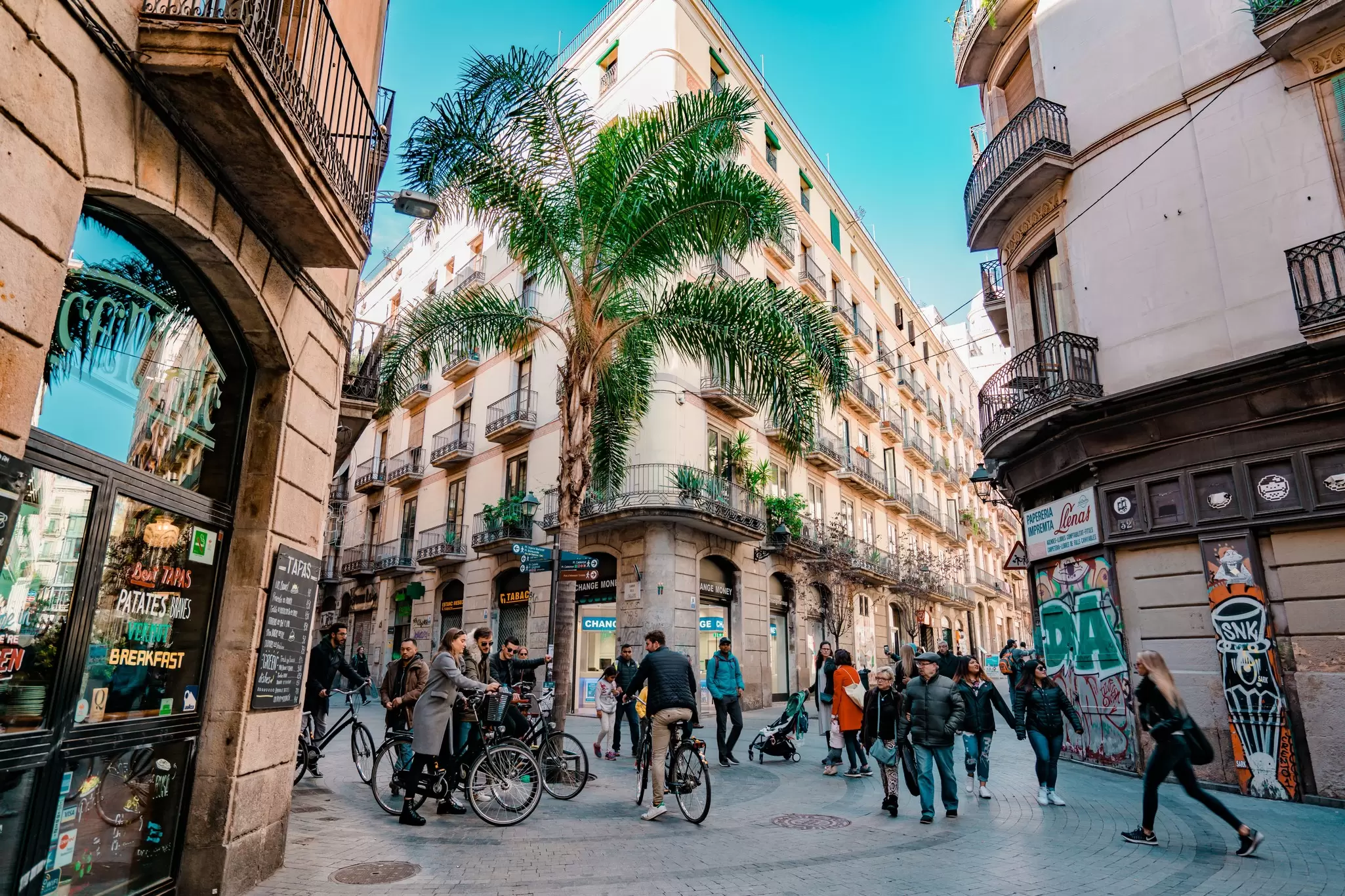 An intersection of narrow streets is filled with pedestrians and cyclists, Barcelona