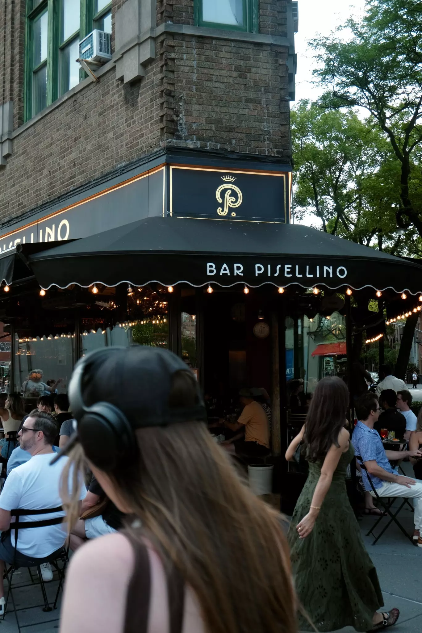 People walk by and sit outside Bar Pisellino in the West Village, NYC