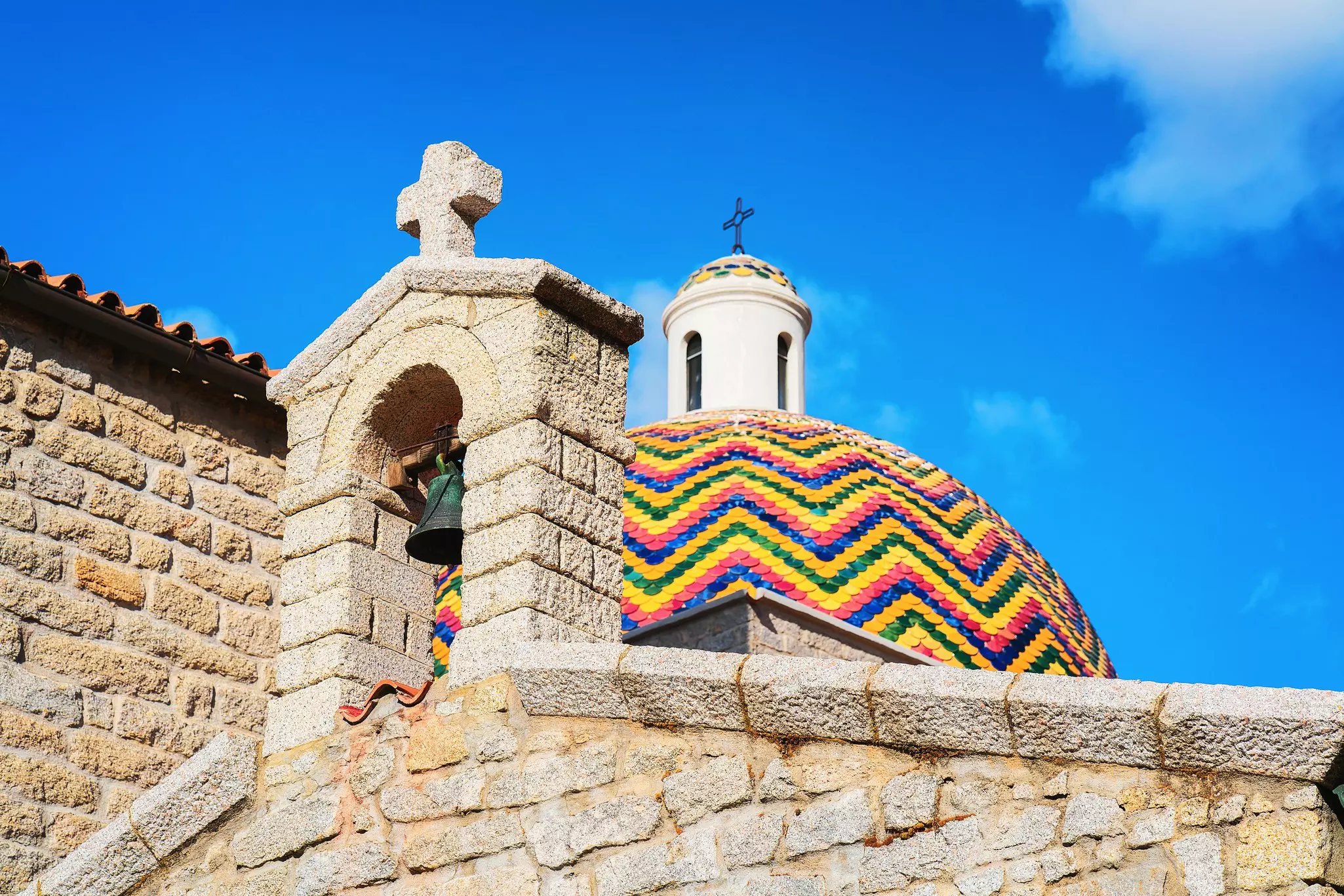 Brightly colored tiles in a zigzag pattern top the dome to a church in Sardinia.