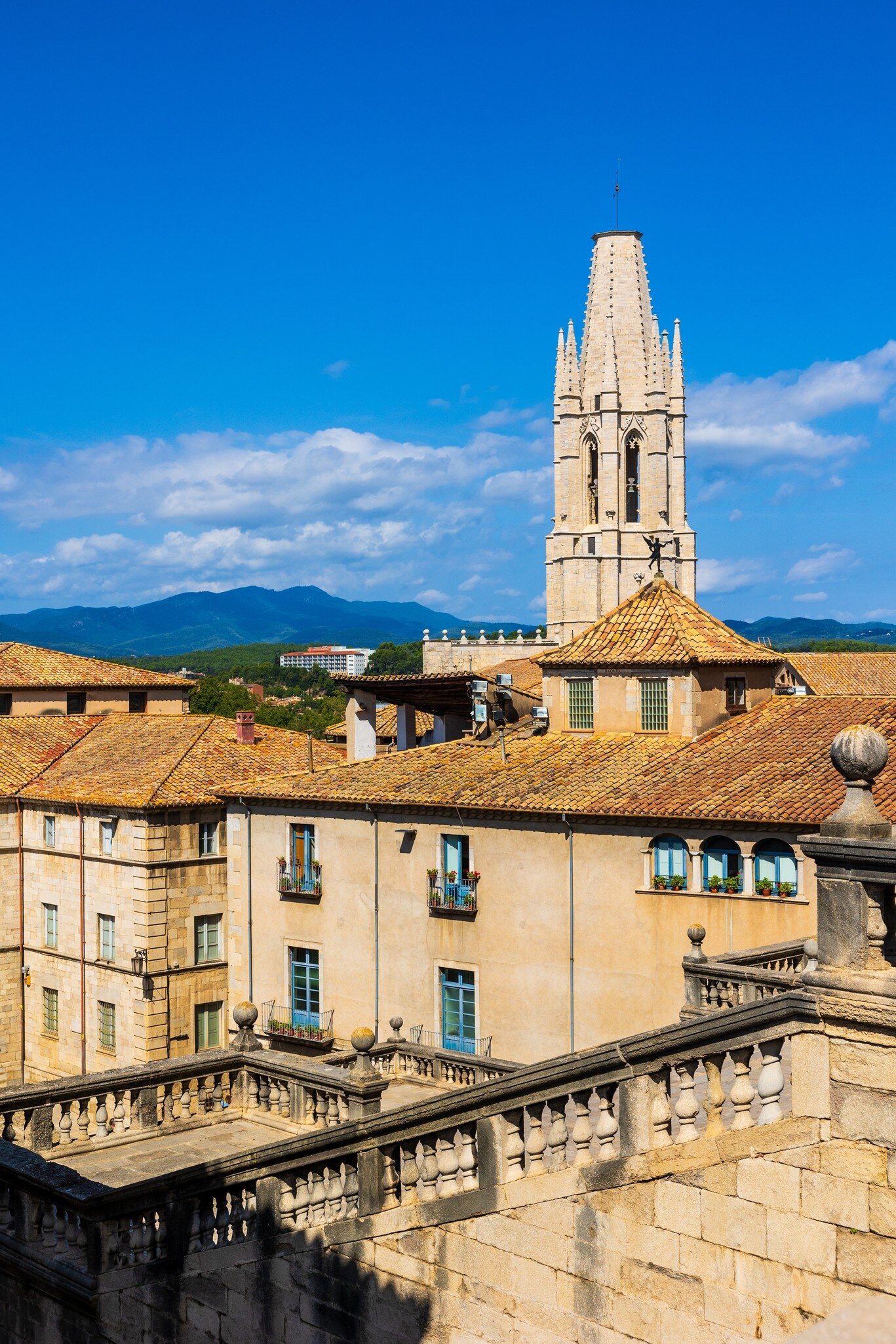 View of the Gothic bell tower of the Basílica de Sant Feliu on a sunny day in Girona, Spain.