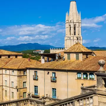 View of the Gothic bell tower of the Basílica de Sant Feliu on a sunny day in Girona, Spain.