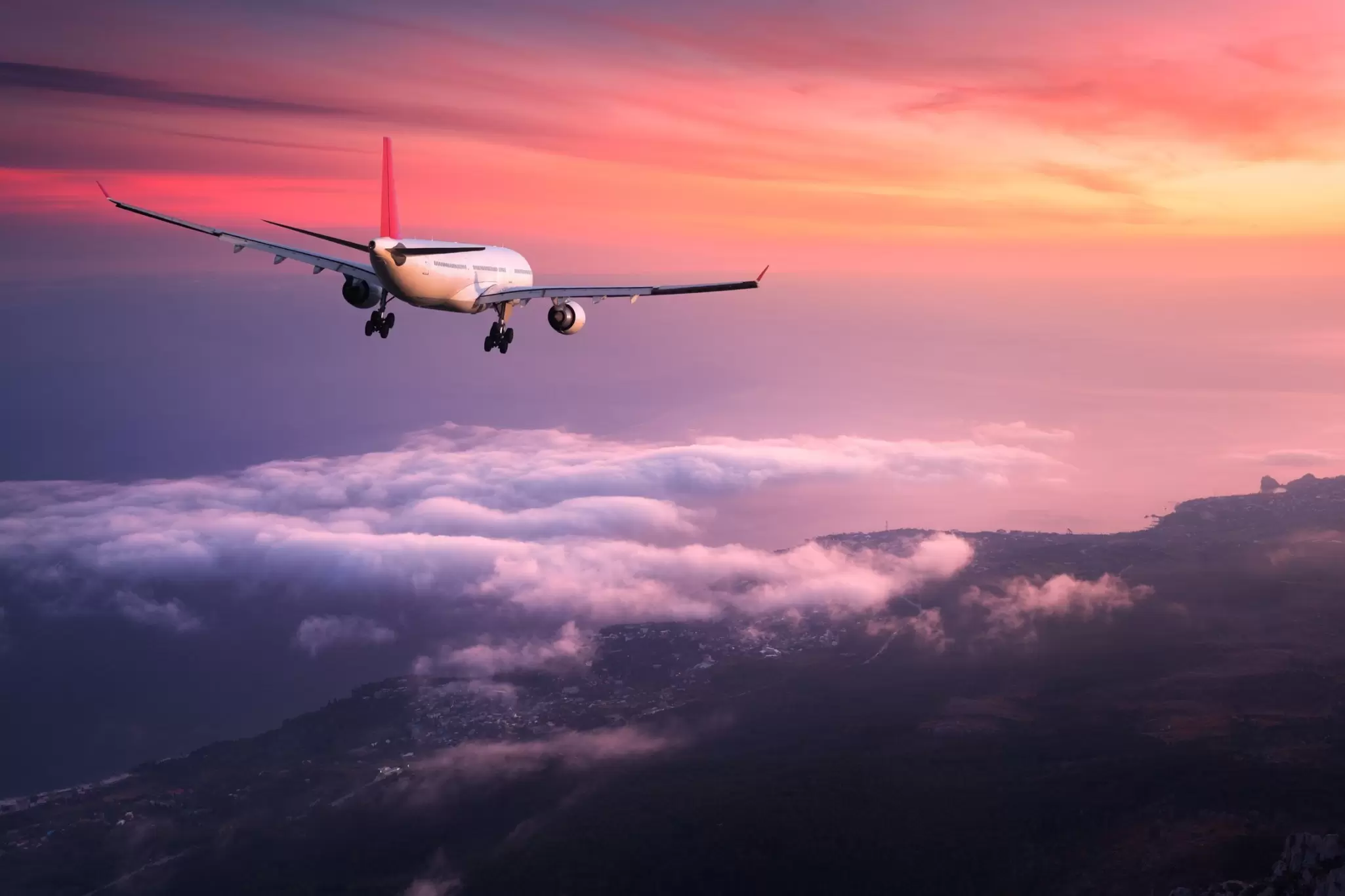 A passenger airplane silhouetted against a sunset sky