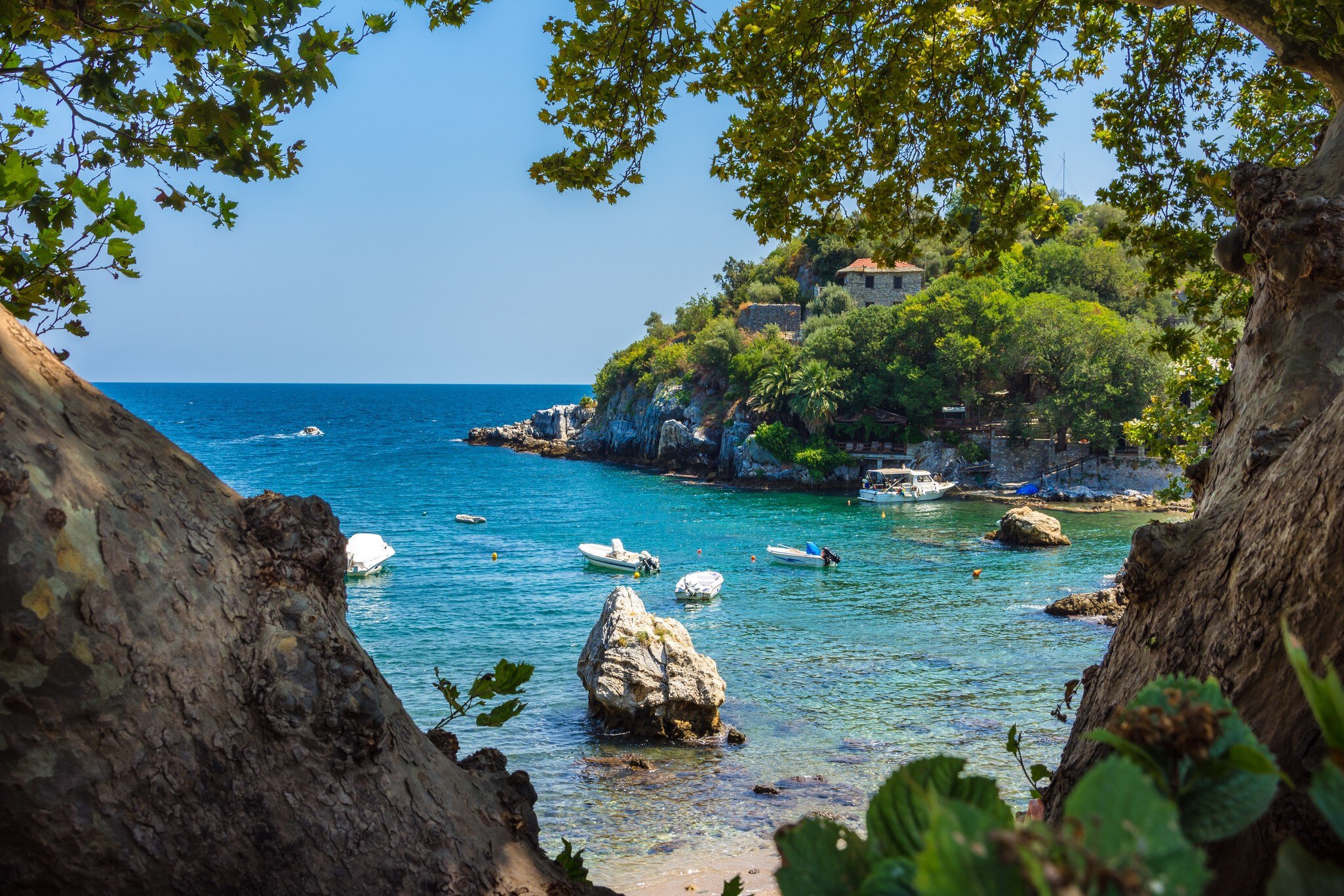 A small cove lapped by turquoise ocean. Several small boats are moored in the bay.