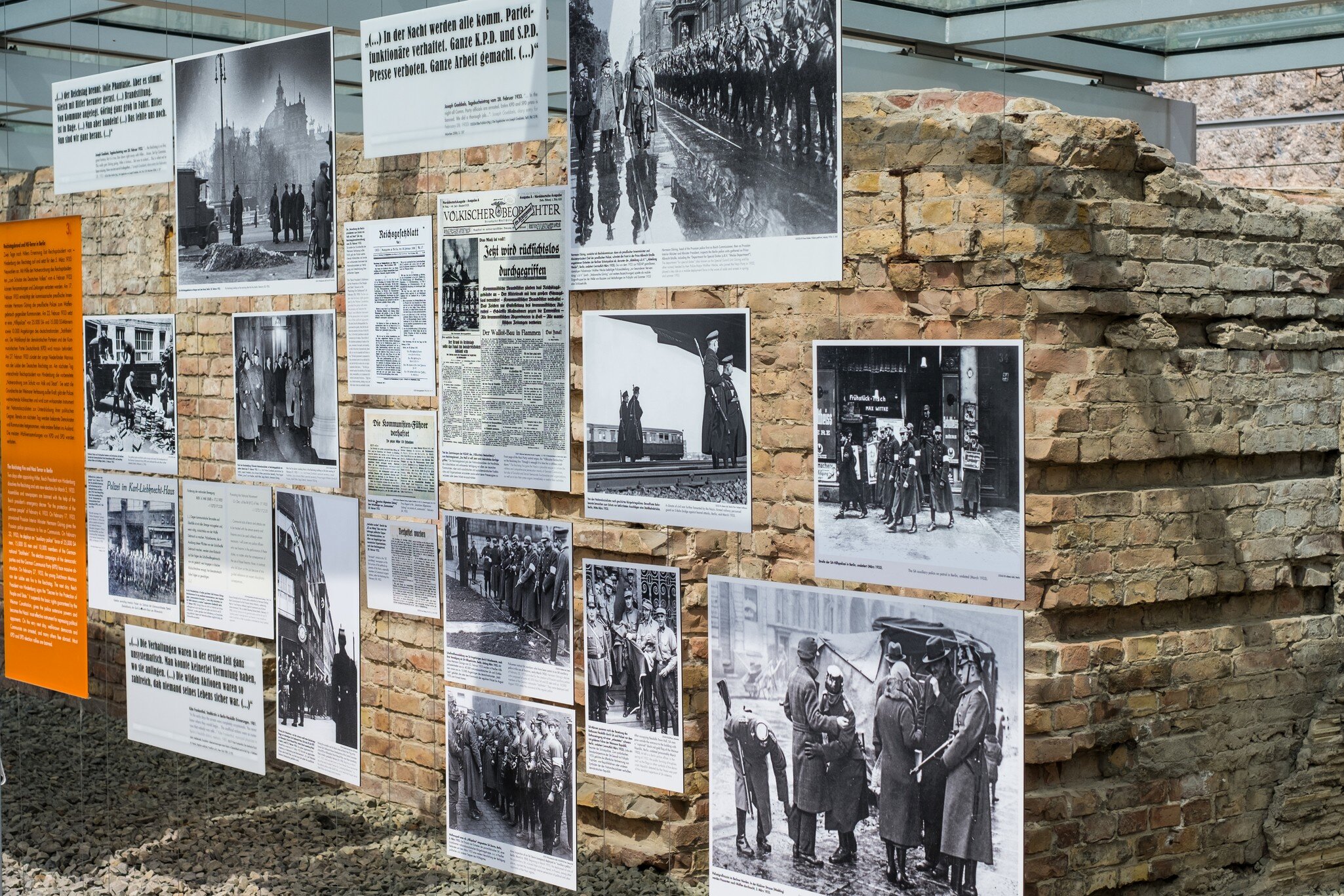 Visitors reading placards beside an excavated cellar wall under a glass canopy