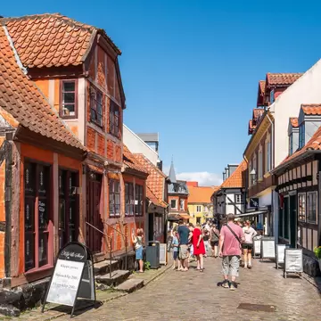 People strolling along cobblestone street Adelgade in old town Ebeltoft, Jutland, Denmark.