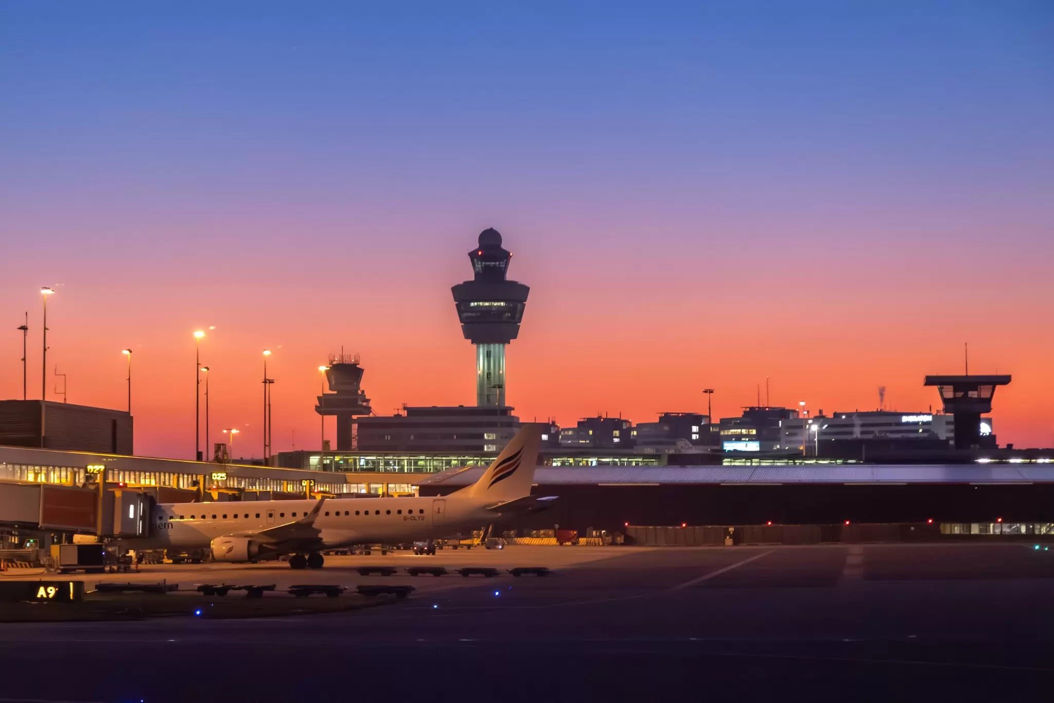 View of airplanes parked at Schiphol Airport at night.