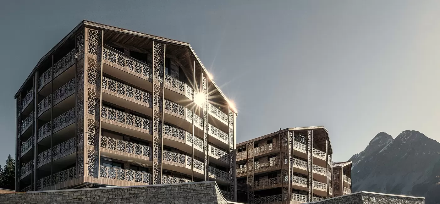 Sun glints off the facade of a large hotel building on a bright day: Valsana Hotel, Switzerland