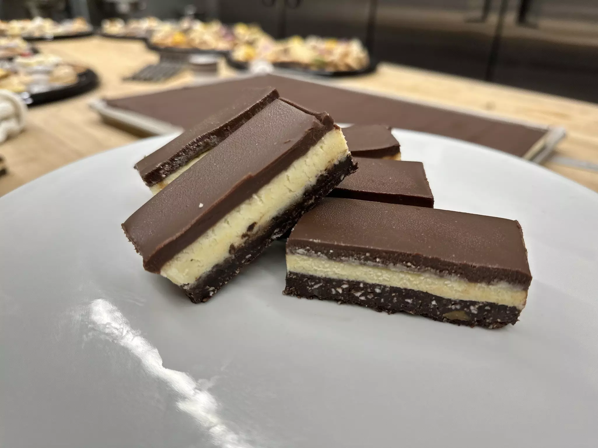 A white plate with several chocolate-based layered bars stacked on it.