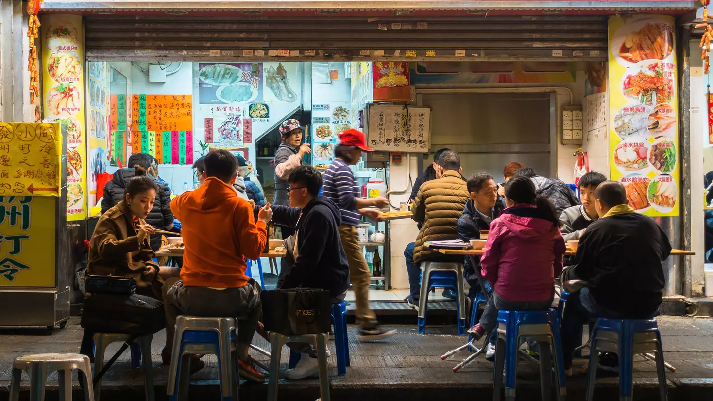Street scene with local people dine at a street vendor in Mong Kok area. Hong Kong