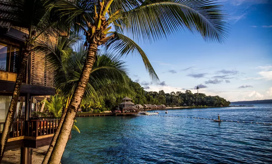 Waterfront resort near Davao with palm trees, wooden cottages on stilts and a jetty over calm blue water