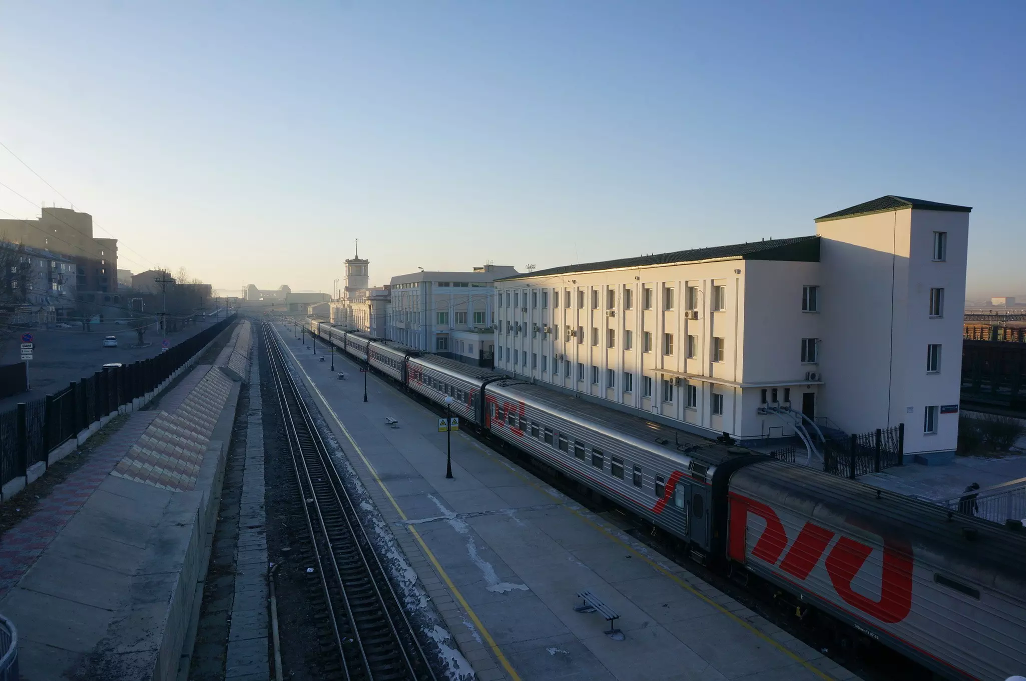 Looking down towards train tracks with on train standing at a platform