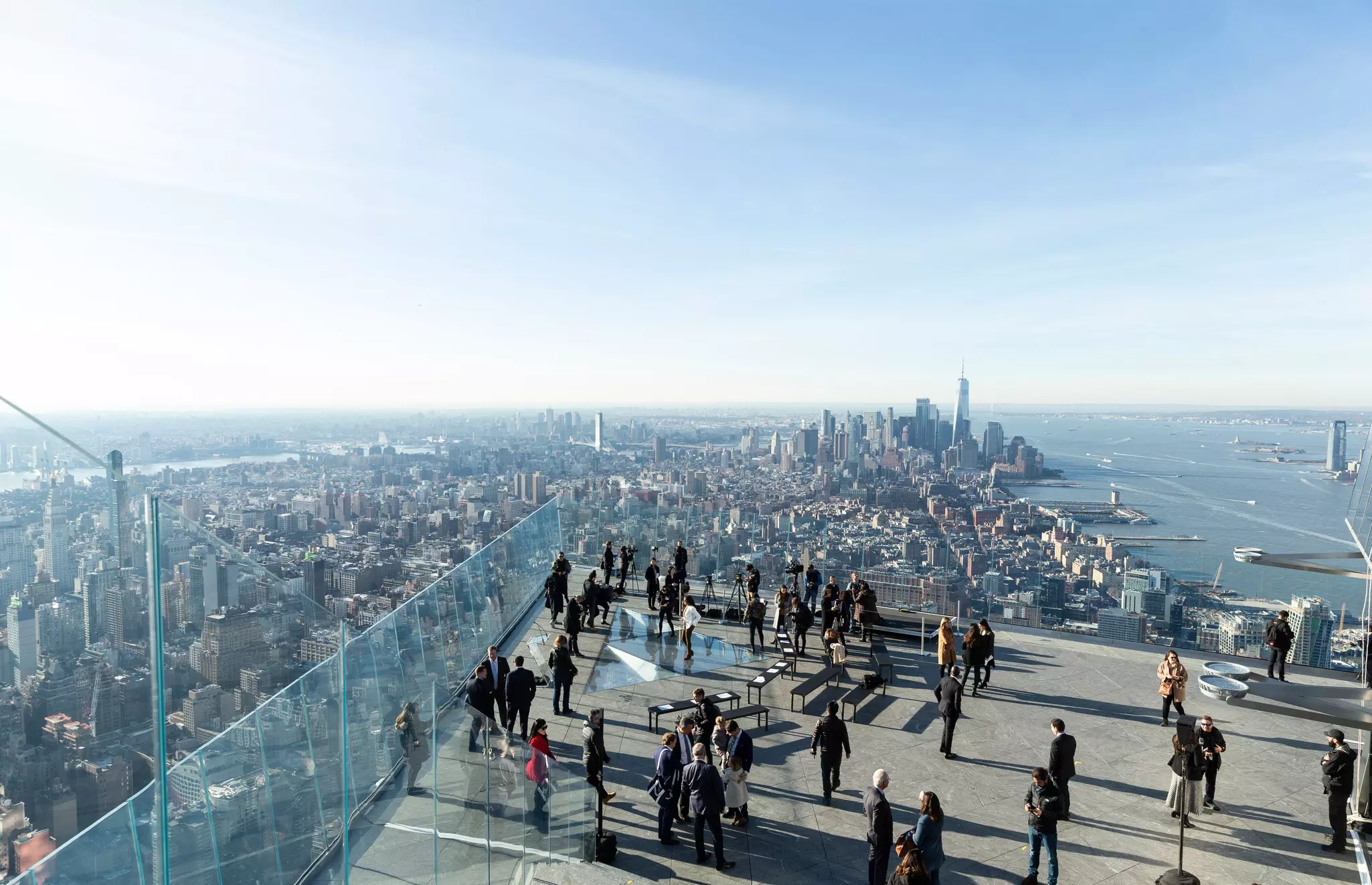 A crowd of people on the glassed-in Edge observation deck in New York City facing downtown.