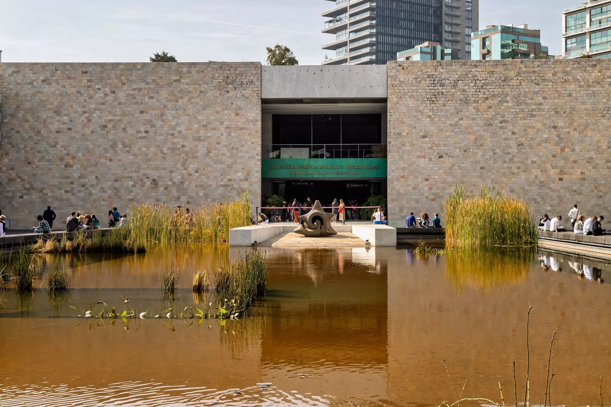 Visitors gather around the central pond and sculpture in the courtyard of the Museo Nacional de Antropología in Mexico City, Mexico.