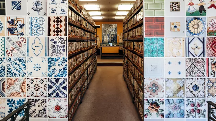Many rows of different painted glazed tiles fill shelves.
