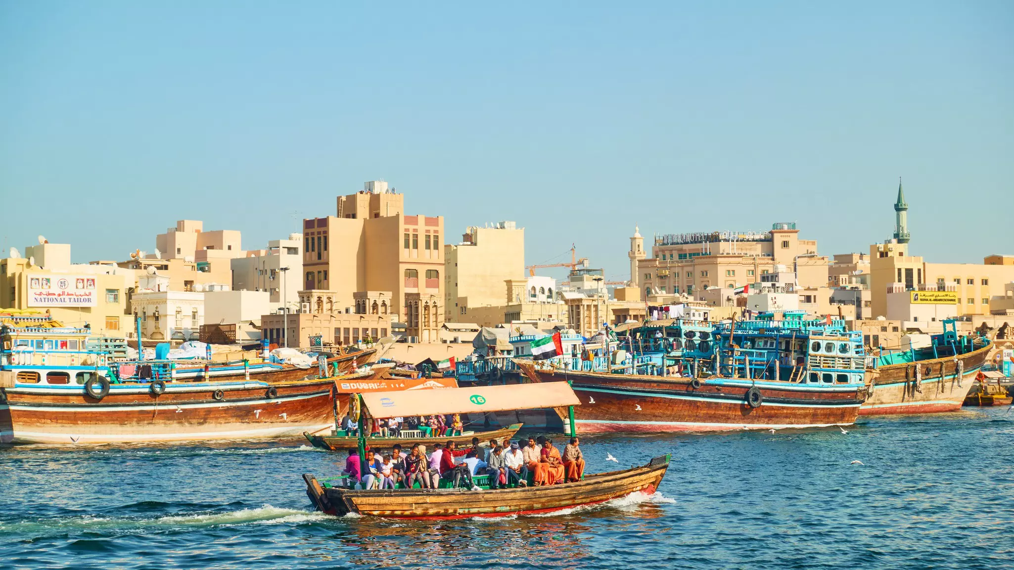 Passengers on traditional boat sail past an old district of Dubai, United Arab Emirates.