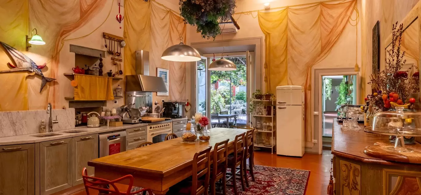 A kitchen with high ceilings, warm lighting and a long table and chairs