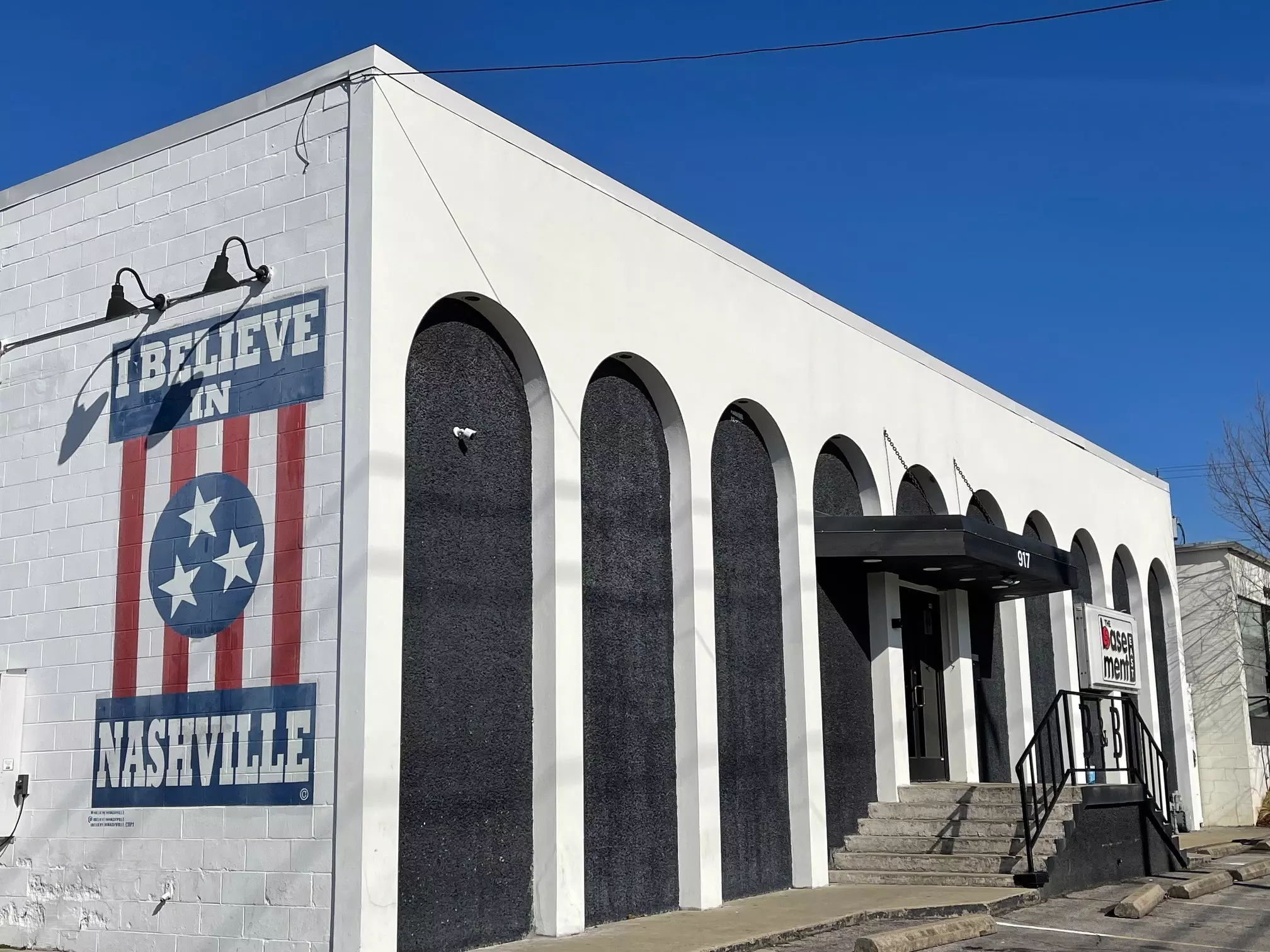 An eerie purple sky glows over a white brick wall with a mural reading I Believe in Nashville, one of the only parts of the Basement East facade still standing after the Nashville tornados