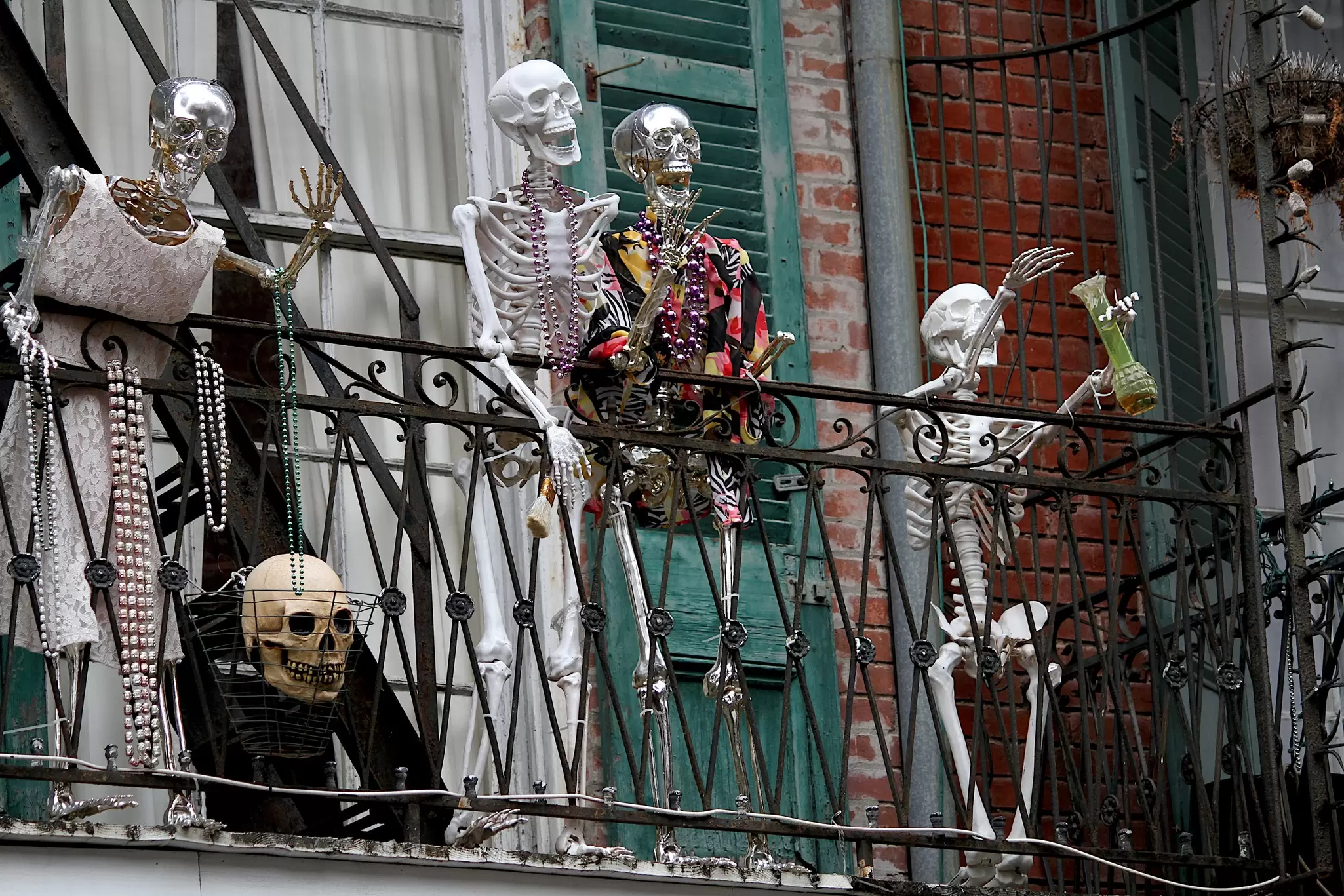 Fake skeleton decorations with Mardi Gras beaded necklaces on a fire escape.