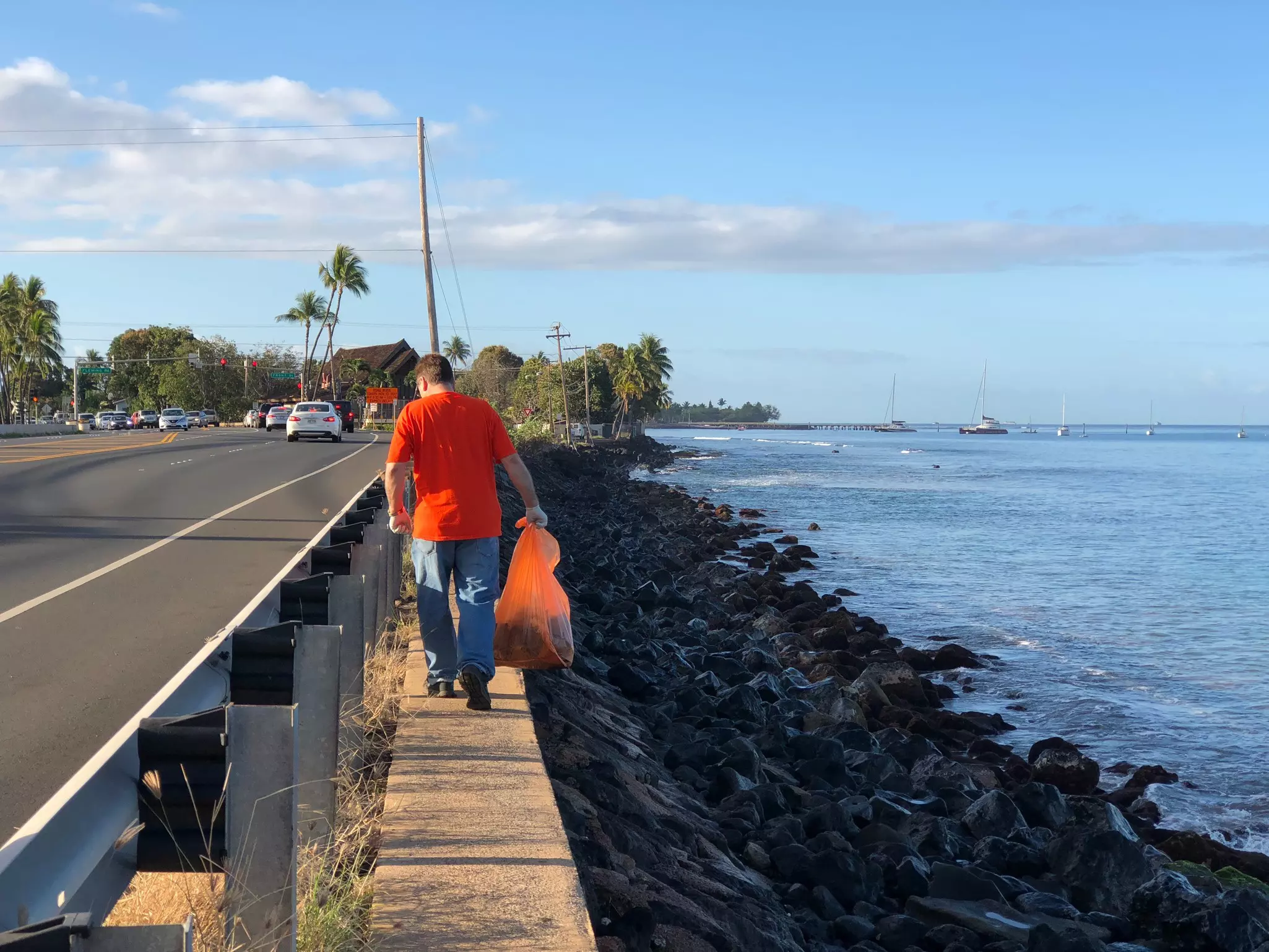 Highway clean up volunteer looking for trash to pick up next to the beach in Lahaina, Maui.