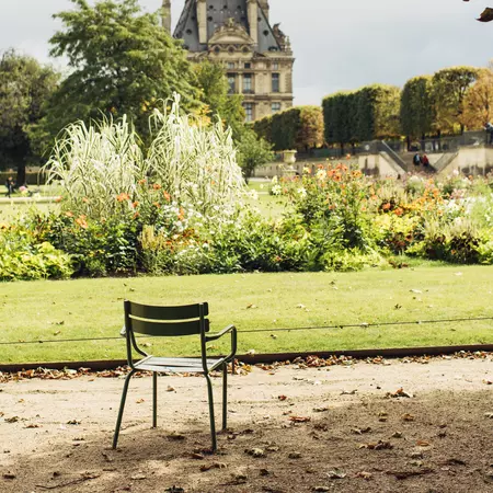 A green chair sits under tree in Jardin des Tuileries in Paris.