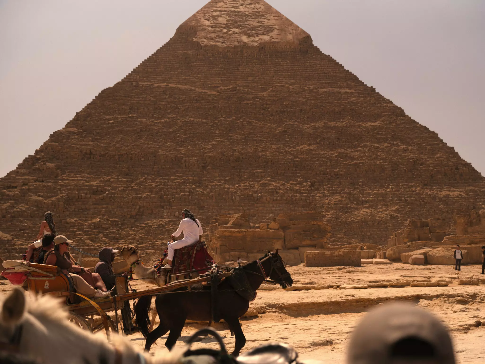 People ride in a carriage near an ancient pyramid.