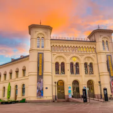 Cream neoclassical building with twin towers and exhibition banners at dusk