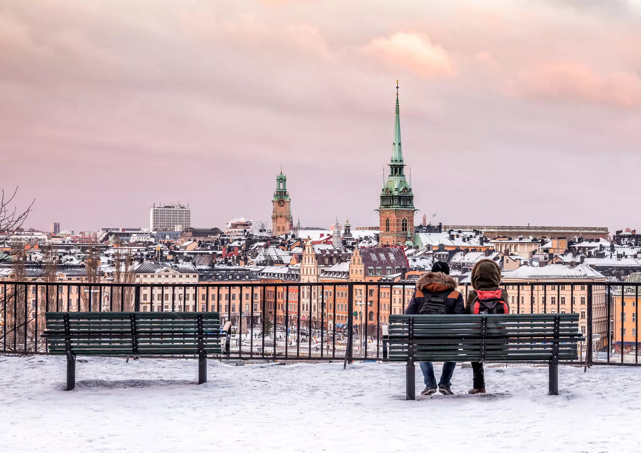 A couple seated on a bench as they look over Stockholm's Old Town.